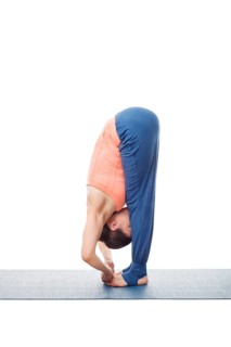 Woman doing Ashtanga Vinyasa Yoga asana Padangushthasana, standing forward bend hand to toe pose