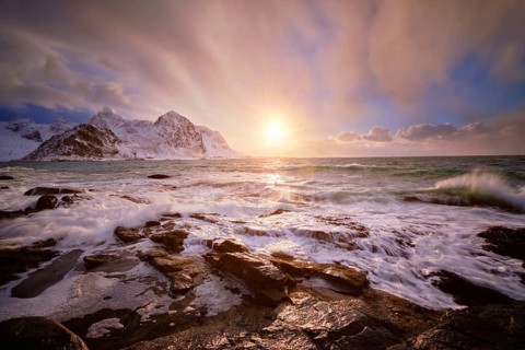 Beach of Norwegian sea on rocky coast in fjord on sunset in winter. Vareid beach, Lofoten islands,
