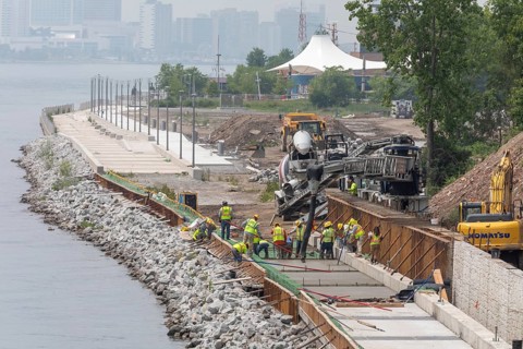 Workers pour cement to complete a section of the Detroit Riverwalk on the site of the former