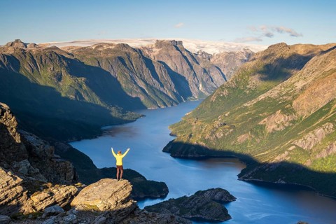 Hiker looking from Seiskallåfjellet into the Nordfjorden, Svartisen Glacier in the background,