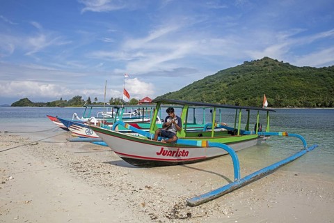 Indonesian tourist guide playing ukulele on outrigger boat on the islet Gili Nanggu, Gili Islands,