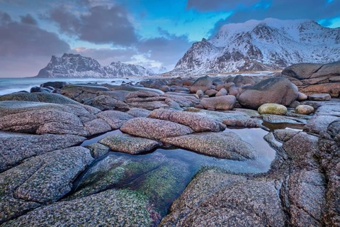 Rocks on beach of fjord of Norwegian sea in winteron sunset. Utakliev beach, Lofoten islands,