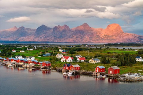 Boathouses of the village Herøy, behind the mountain range Seven Sisters, light mood, island Herøy,