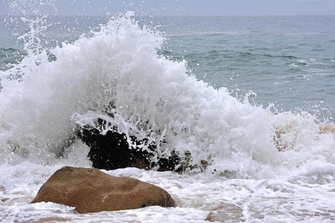 Wave crashing into boulder in the surf at the Côte Sauvage, Wild Coast, Quiberon, Brittany, France,