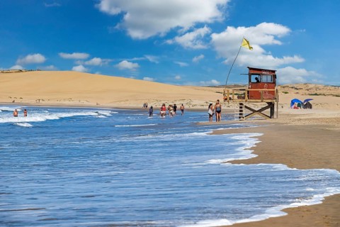 Lifeguard tower and tourists walking on the beach at Barra de Valizas, seaside resort, balneario