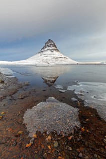 Kirkjufell, nunatak hill covered in snow reflected in water of fjord on the Snæfellsnes peninsula