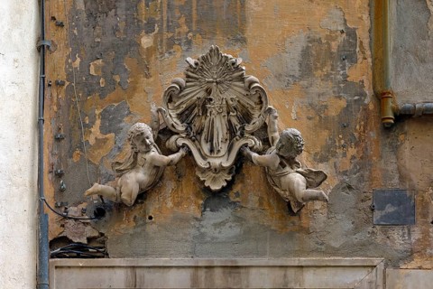 Putti holding an ecclesiastical symbol above an entrance door to a crypt, historic centre, Piazza