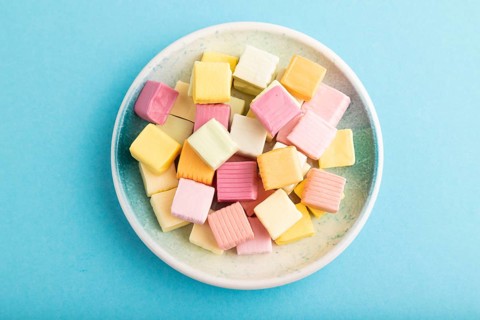 Various fruit jelly chewing candies on plate on blue pastel background. apple, banana, tangerine,