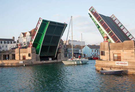 Town bridge raised to allow a yacht to pass into the marina in Weymouth harbour, Dorset, England,