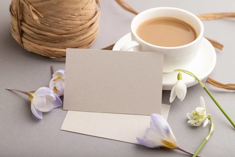 Gray paper business card mockup with spring snowdrop crocus and galanthus flowers and cup of coffee