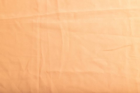 Fragment of smooth orange linen tissue. Top view, flat lay, natural textile background and texture