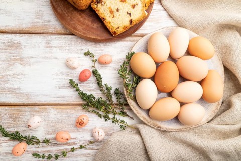 Homemade easter pie with raisins and eggs on plate on a white wooden background and linen textile.