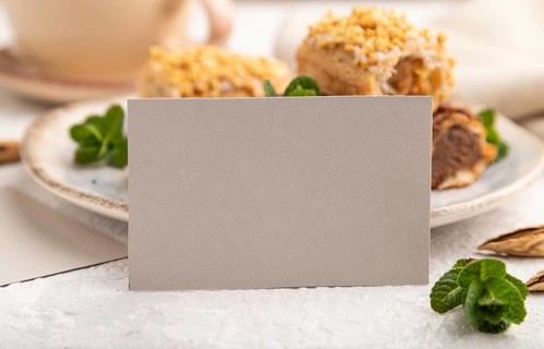 Gray paper business card and set of eclair on gray concrete background. side view, close up,