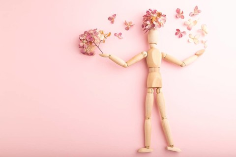 Wooden mannequin holding hydrangea flowers on pink pastel background. copy space, isolated, spring,
