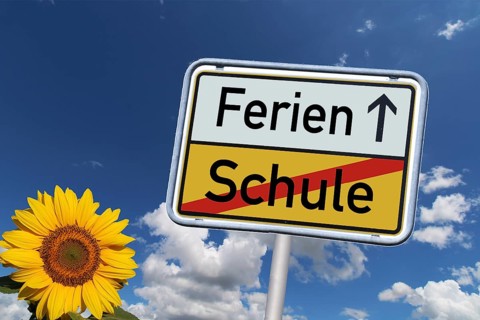 Symbolic image: German town exit sign with the words Schule/Ferien against a blue sky