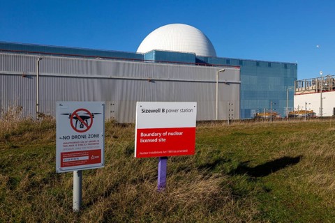 Signs boundary and no drone zone with white dome of Sizewell B power station, Suffolk, England, UK