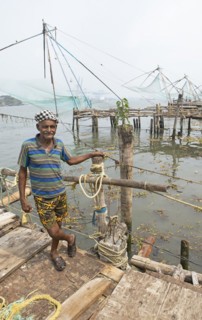 Indian fisherman standing at Chinese fishing nets, behind the Arabian Sea, Kochi, Kerala, India,