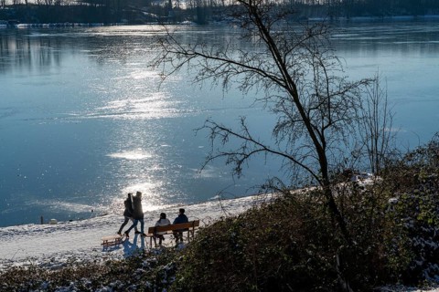 Winter in the Ruhr area, Lake Baldeney, snow-covered, partly frozen lake, walkers on the lakeside