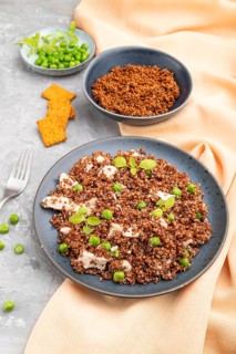 Quinoa porridge with green pea and chicken on ceramic plate on a gray concrete background and