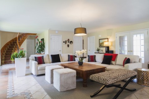 Beige upholstered sofas with colourful cushions, wooden coffee table and zebra motif ottoman in
