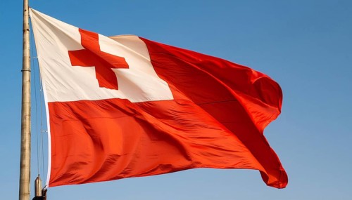 The flag of Tonga, Pacific island state, flutters in the wind, isolated against a blue sky