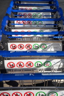 Close up of line of stacked luggage trolleys with rules about use, Malaga airport, Spain, Europe