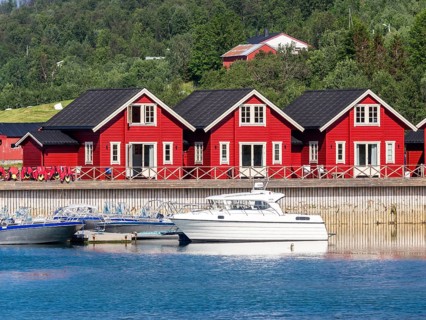 Typical red-white wooden holiday cottages, pier with leisure boats, Lenangsstraumen, Lyngen
