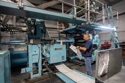 Liberal, Kansas, Danny Moura checks papers coming off the printing press at the Leader & Times.
