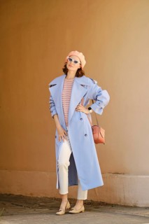 Trendy woman in long blue trench coat posing outdoors