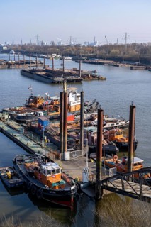 Hamburg harbour, Travehafen, working boats and barges, jetty, city skyline in the background,
