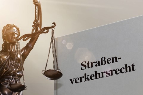Symbolic image: Textbook on traffic law and a Justitia