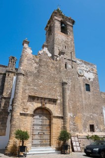 Historic church with high tower, massive entrance and stony walls under a clear sky, Iglesia del