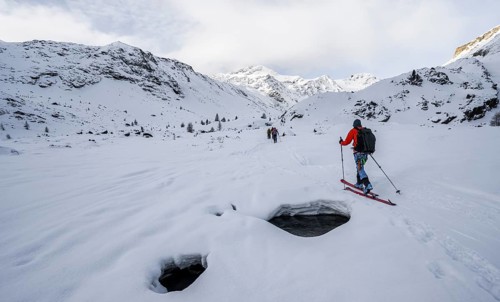 Ski tourers ascending in the rear Martell Valley, snow-covered mountain peak Monte Cevedale behind,