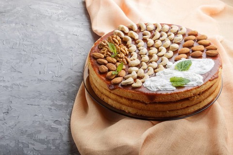 Homemade cake with caramel cream and nuts on a gray concrete background. side view, copy space