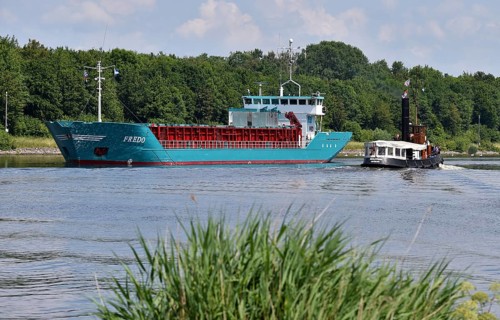 Steam tug Woltman and cargo ship Fredo sailing in the Kiel Canal, Schleswig-Holstein, Germany,