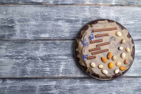 Homemade chocolate brownie cake with caramel cream and almonds on a gray wooden background. top