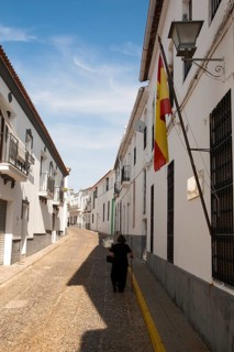 Woman walking along a quiet street in village of Jabugo, Sierra de Aracena, Huelva province, Spain,