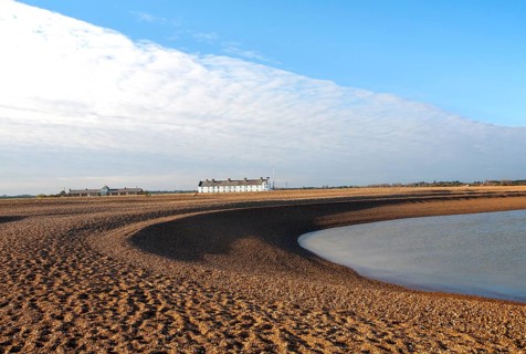 Frontal clouds passing over Coastguard Cottages shingle beach at Shingle Street, Suffolk, England,