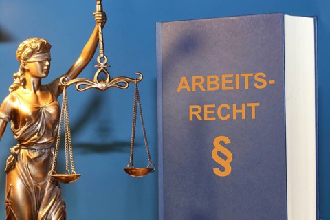 Symbolic image: Labour law reference book and a Justitia