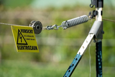 Electric fence on a pasture, warning sign, electric shock