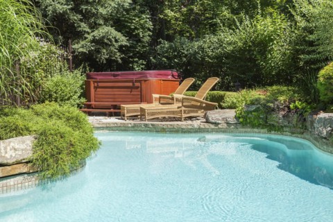 In-ground swimming pool surrounded by copper coloured wrought iron metal security fence and various