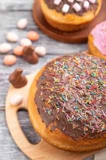 Homemade glazed and decorated easter pies with chocolate eggs and rabbits on a gray wooden