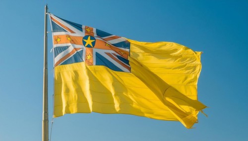 The flag of Niue, an island state in the Pacific Ocean, flutters in the wind, isolated against a