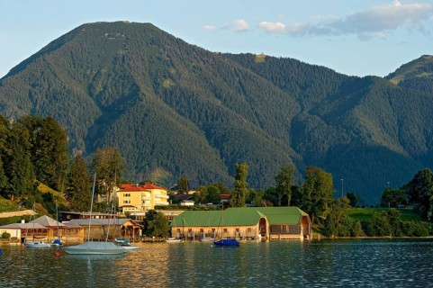 Tegernsee with sailing boats and boat huts, warm evening light, town Tegernsee, mountain Wallberg,