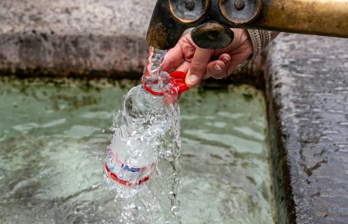 Water fountain, a woman fills drinking water into a small plastic bottle, Munich, Bavaria, Germany,