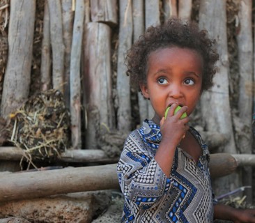 Amhara region, little girl eating fruit, Ethiopia, Africa