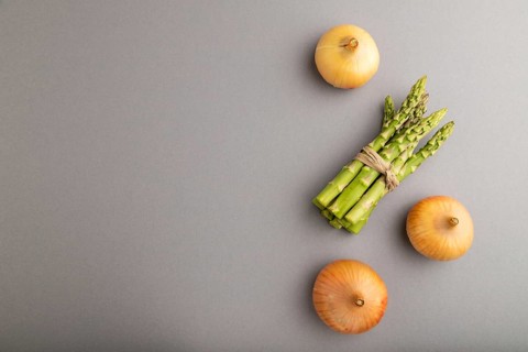 Bunch of fresh green asparagus and onion on gray pastel background. Top view, flat lay, copy space.