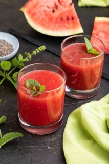 Watermelon juice with chia seeds and mint in glass on a black concrete background with green