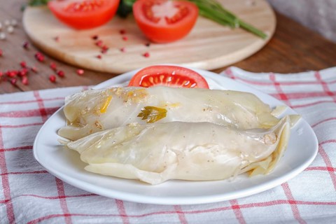 Cabbage rolls with beef, rice and vegetables on a linen tablecloth on a brown wooden background.