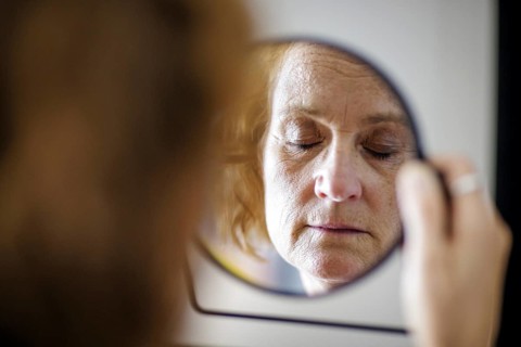 Symbol photo. An elderly woman with closed eyes can be seen in a mirror. Berlin, 13.08.2024